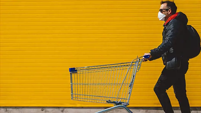 Man wearing a mask and pushing a trolley