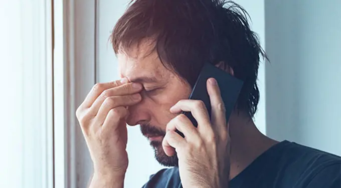 Man on the phone and holding his head
