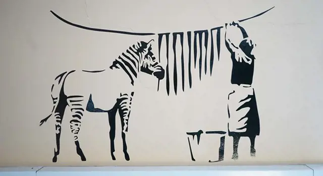 Drawing of a zebra and lady on a wall