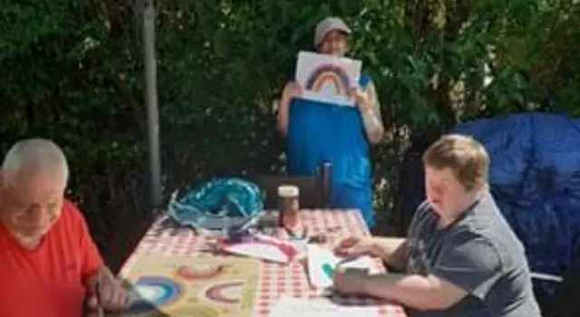 People at table outside drawing rainbows